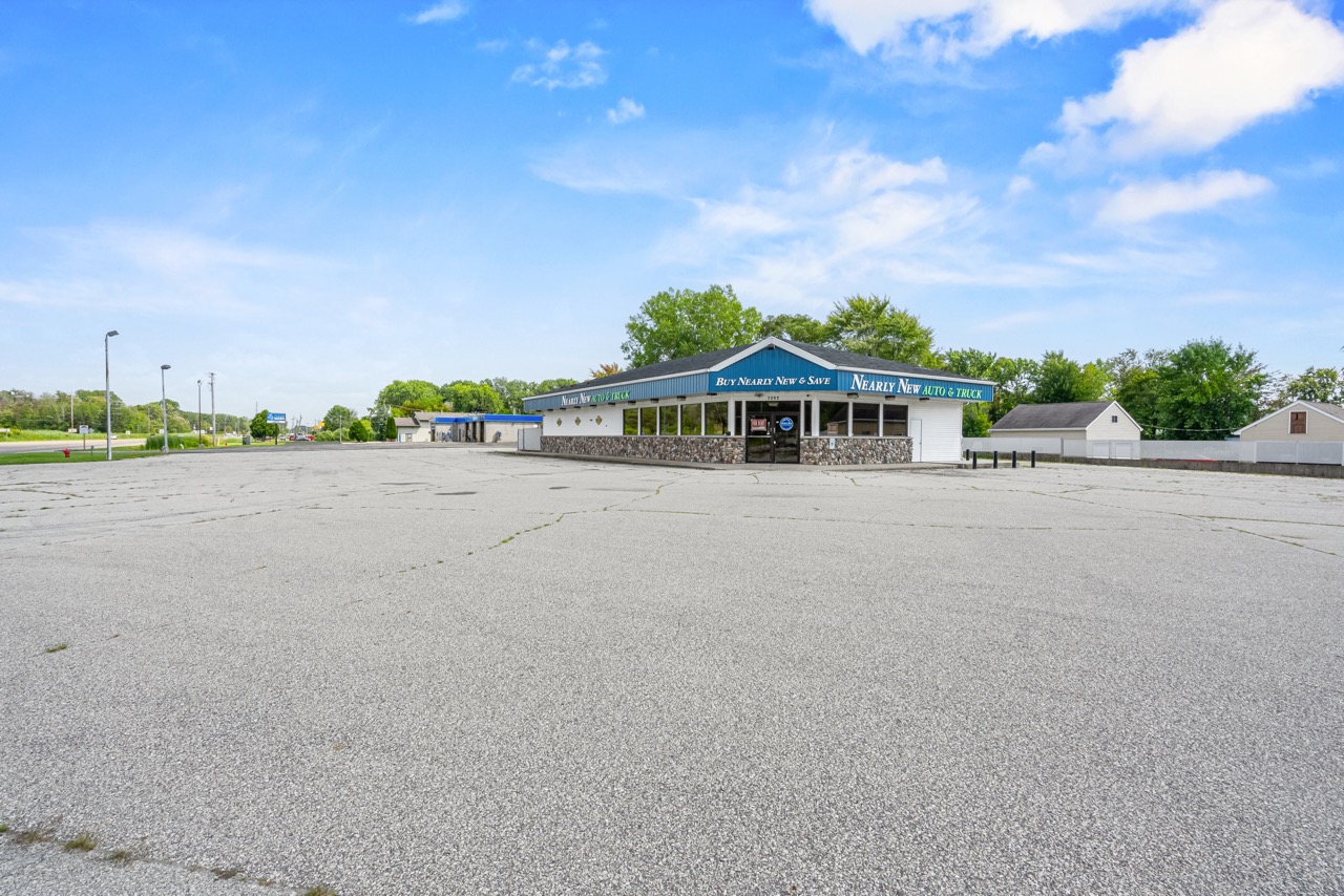 Wide-angle view of the commercial property at W7293 HWY 10 & 114 in Menasha, featuring a large parking lot and the building with stone facade and large windows.