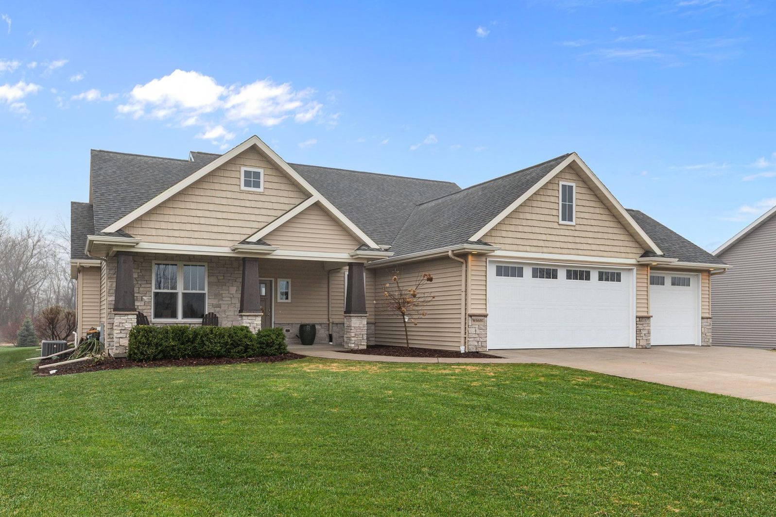 Wide front exterior view of W6681 Charleen Ln in Greenville, WI with blue sky, covered porch, and 3-car garage
