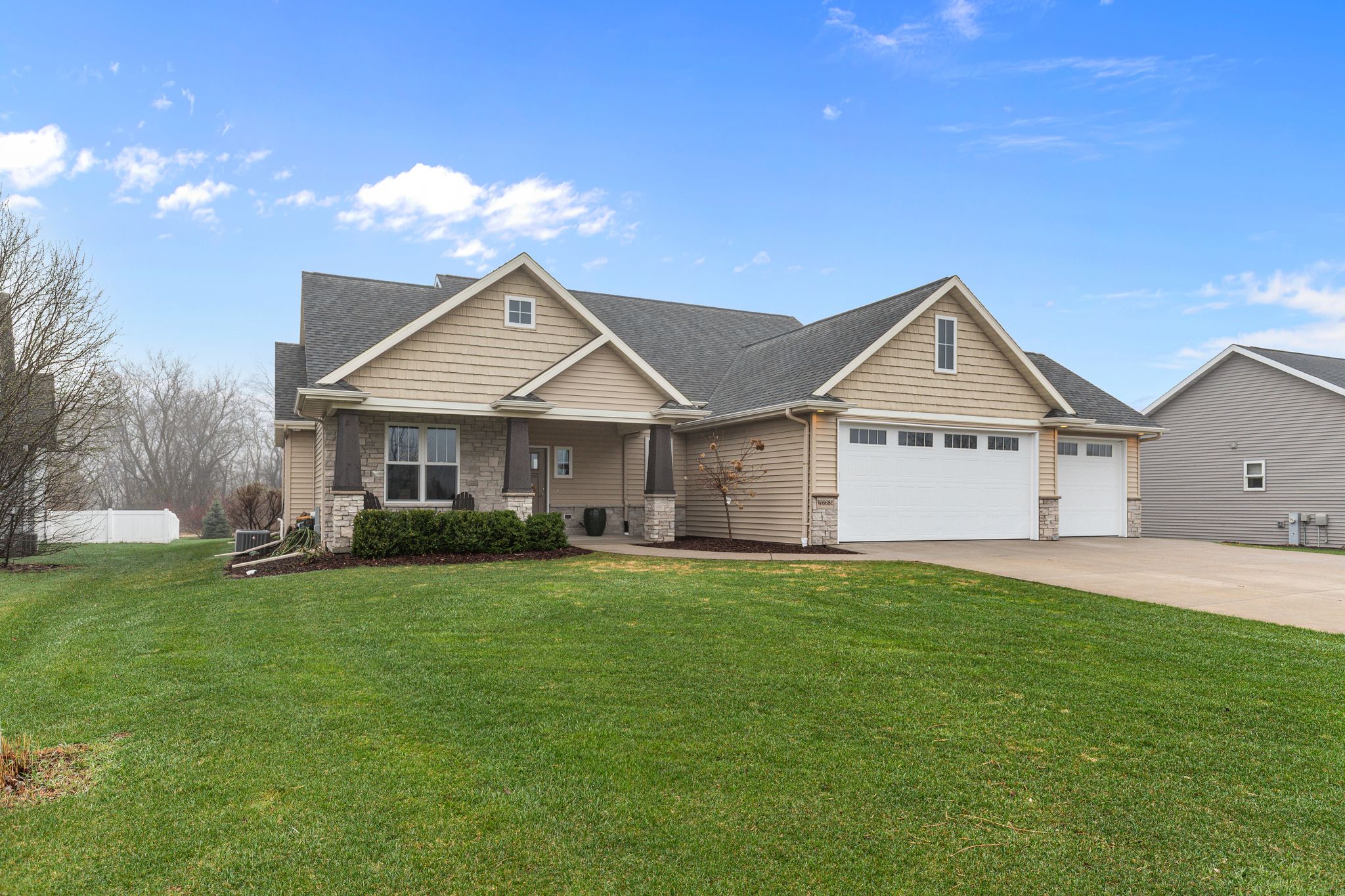 Wide front exterior view of W6681 Charleen Ln in Greenville, WI with blue sky, covered porch, and 3-car garage